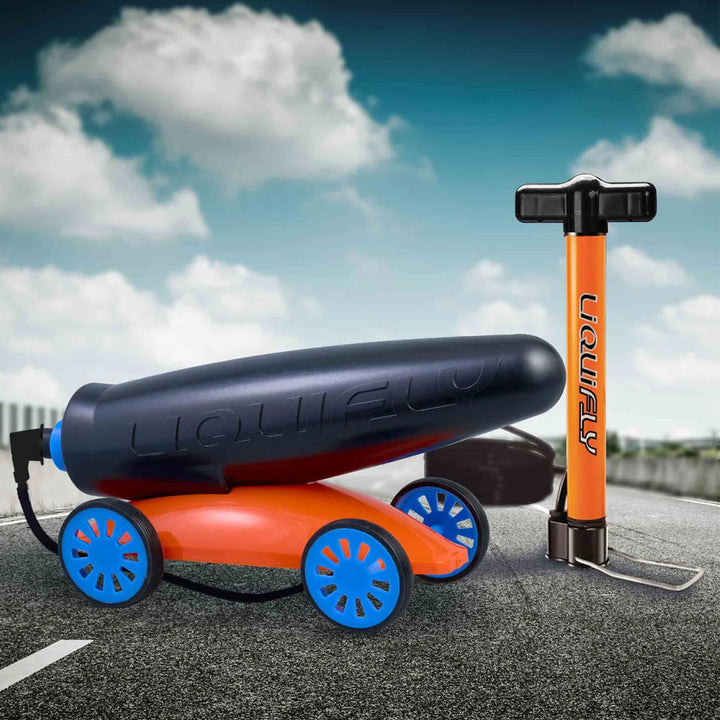 A black and orange Liquifly Water Car STEM toy featuring blue wheels and an attached hand pump, set on a road with a cloudy sky in the background. This water powered Jet Car is perfect for a fun science experiment.