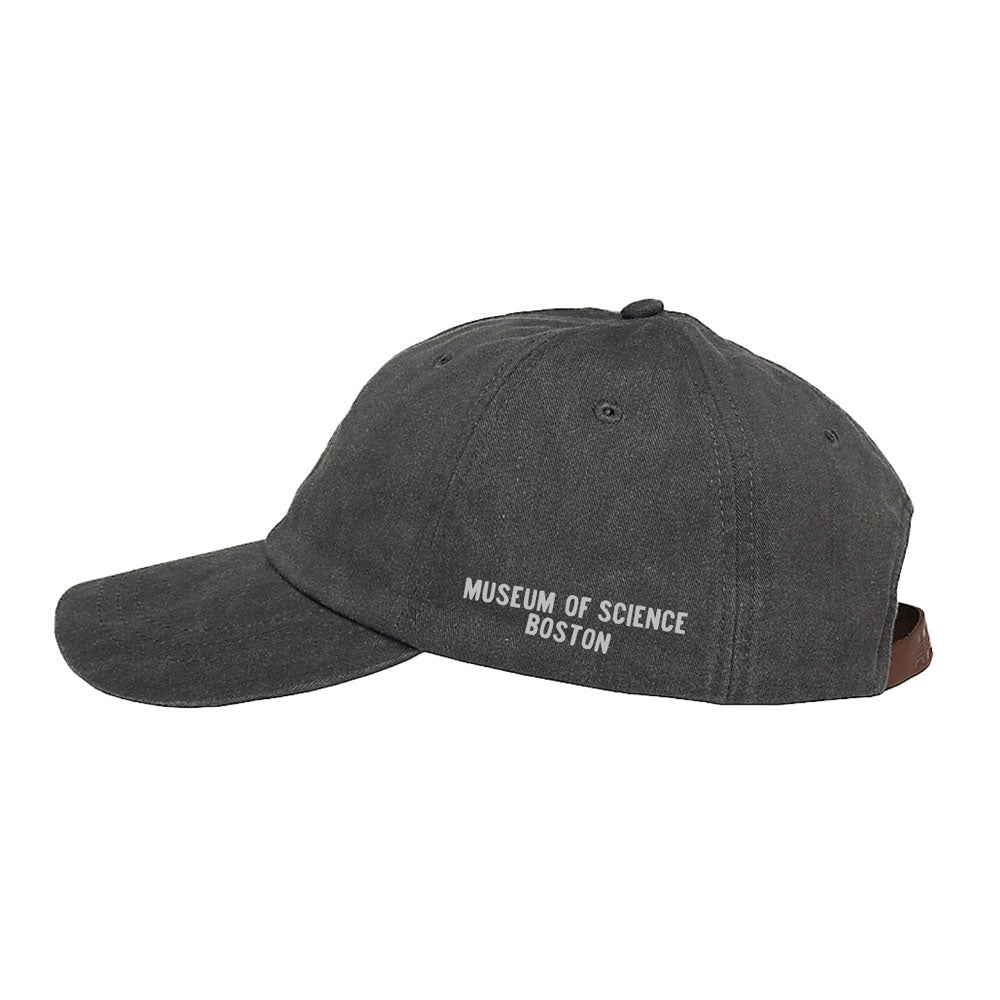 The Museum of Science Boston Cliff the Dino Skull Cap is shown in a left side profile in dark gray, featuring “MUSEUM OF SCIENCE BOSTON” embroidered in white on the side. Designed with an adjustable back strap for comfort, it makes a perfect gift for any paleontologist.