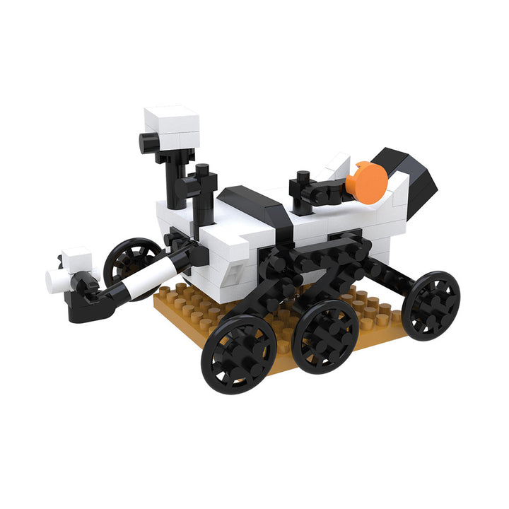 Introducing the Space Mystery Mini Blocks set—a small model rover constructed from LEGO-style bricks, featuring black wheels, a white and black body with an orange detail, and a camera mast. Displayed on a tan base, this collectible rover is perfect for building problem-solving skills and sparking curiosity about space exploration.