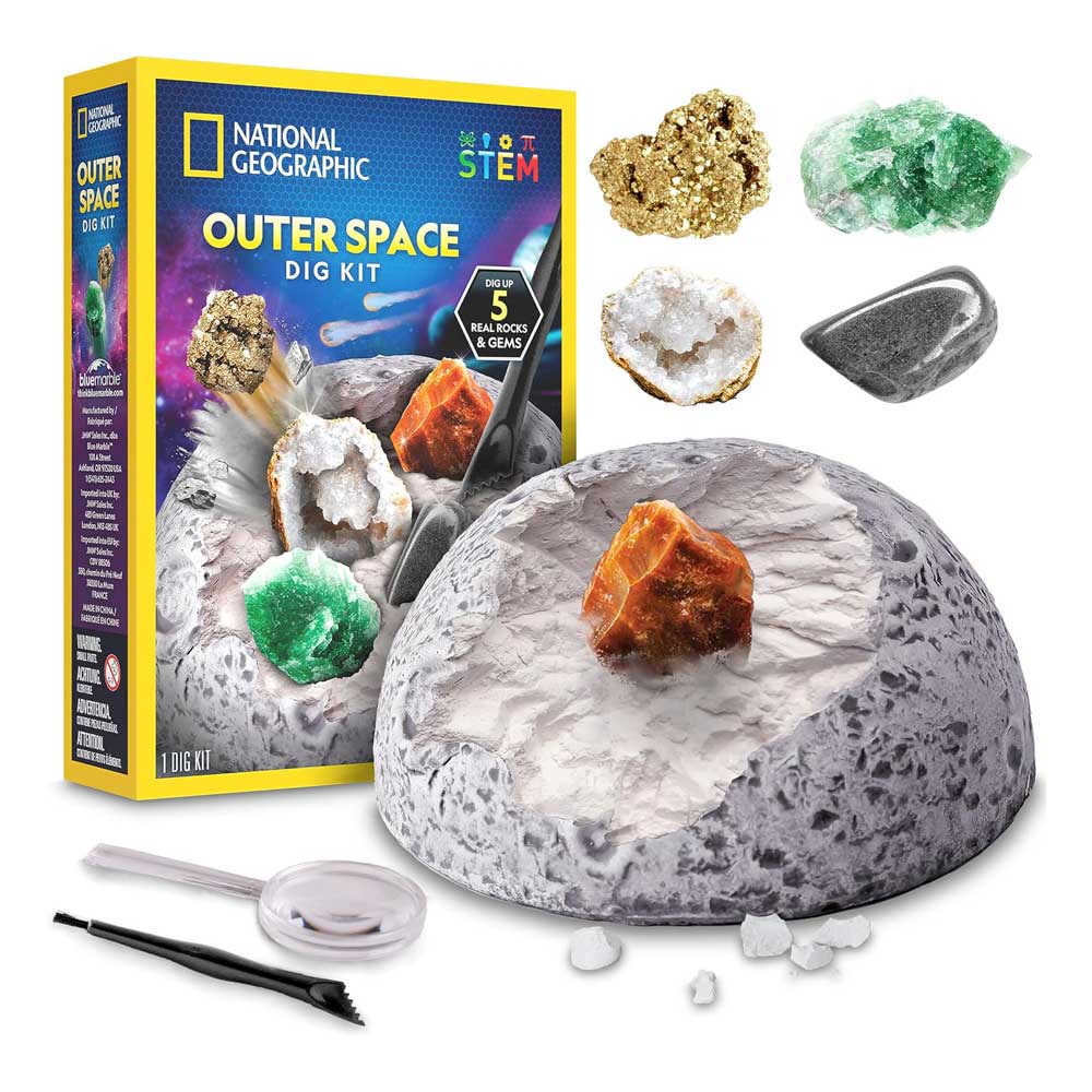 Displayed on a white background are the Outer Space Dig Kit box, a gray digging dome, five gemstones, a black brush, a chisel, and a magnifying glass. The Outer Space Dig Kit is an engaging educational science kit that offers an exciting STEM activity set for young explorers.